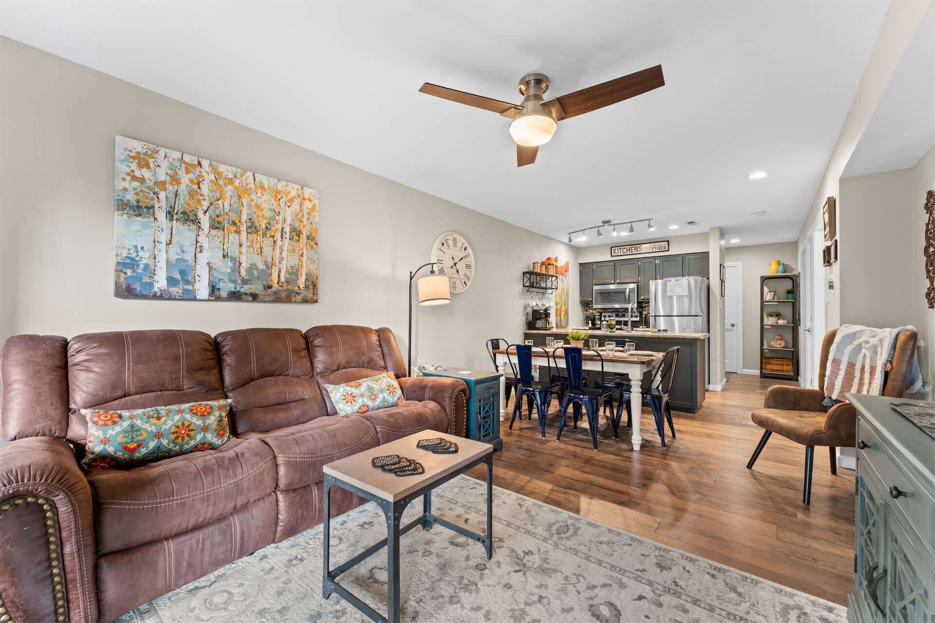 A living room with a brown leather sofa, a small table, and a ceiling fan.