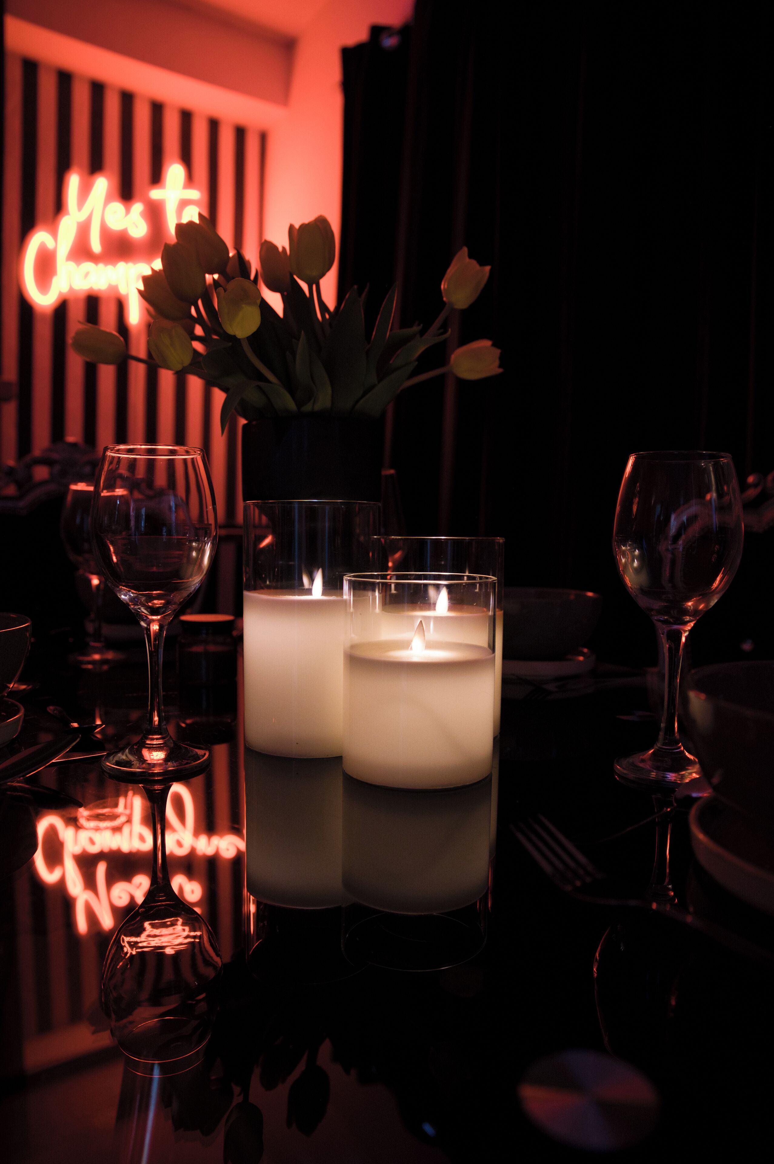 Une table décorée de bougies, d’un vase de fleurs et de verres à vin.