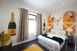 Ein Hotelzimmer mit einem großen Bett, Vorhängen, einem Fenster und Wanddekorationen, darunter Champagnerflaschen und Pferdeköpfe.