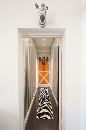 Ein Flur mit einem Zebra-Muster Teppich, einer Zebra-Kopf-Skulptur und einer Pferd-Kopf-Skulptur.