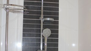 Une douche équipée d’un pommeau de douche à effet pluie, d’un pommeau de douche à main et d’une brosse à main.