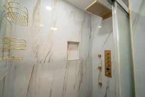 A bathroom with marble walls, a shower with a control panel, and gold-colored fixtures. - Family or work group relaxation at a peaceful place in the heart of Midland (Midland)