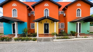 A multi-story building with a central entrance, multiple windows, and a tiled driveway. - Villa Augustas (Gros Islet)