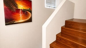 A wooden staircase with a painting of a sunset scene on the wall. - Villa Augustas (Gros Islet)
