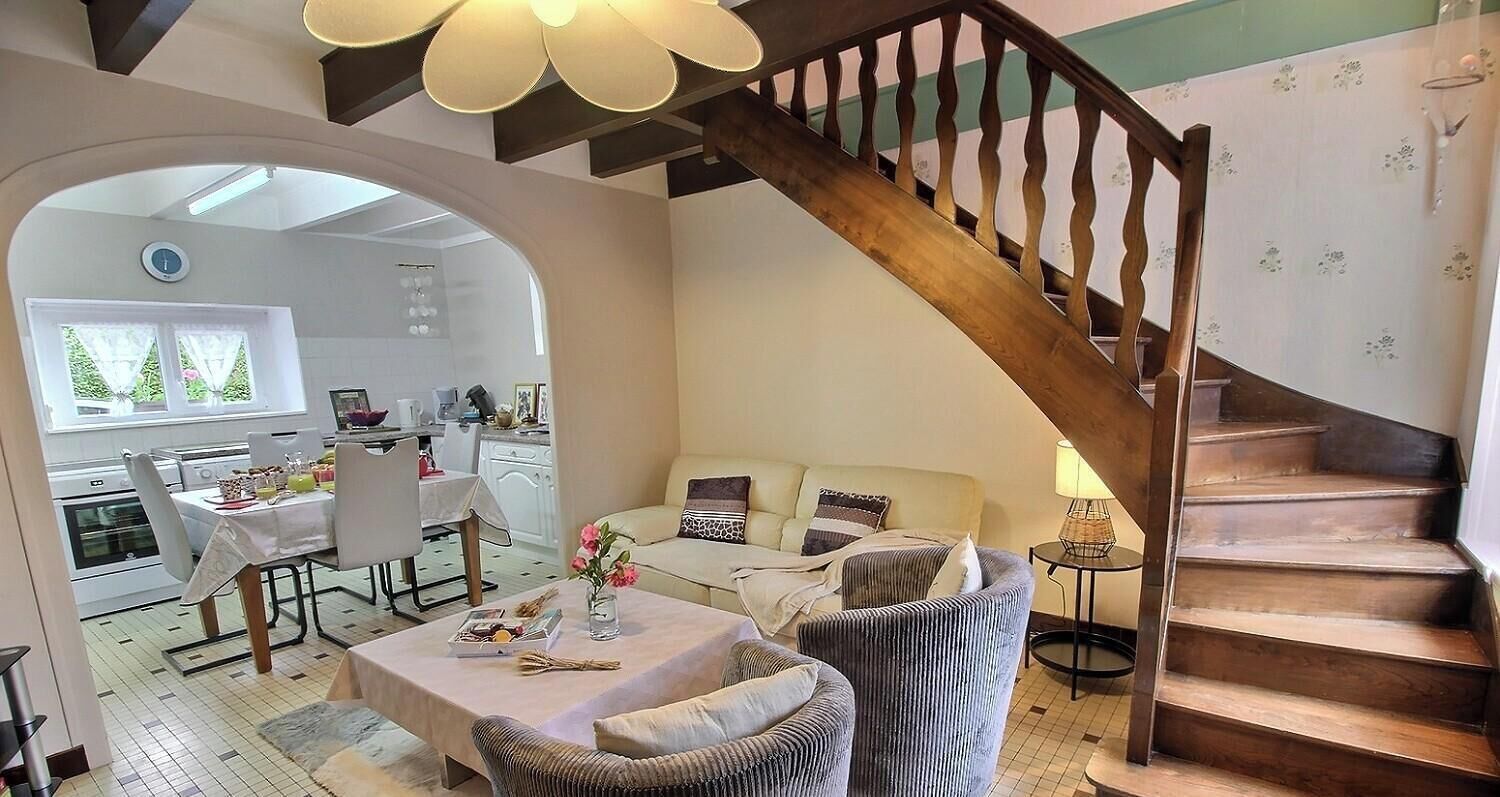 A living room with a sofa, a dining table, and a staircase.