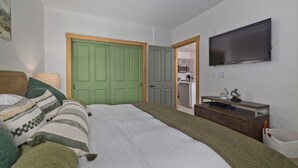 A bedroom with a bed, a television, a desk, and a green door. - Juniper Springs Resort with Panoramic Views - Luxury Mountain Escape (Mammoth Lakes)