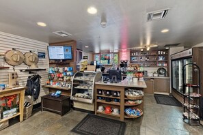 Un magasin où l’on trouve une variété d’articles présentés sur des étagères, un comptoir avec un ordinateur et une vitrine où sont exposés les produits.