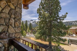 Un bâtiment en pierre doté d’un balcon donnant sur un paysage montagneux et sur un chalet.