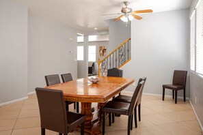 Ein Esszimmer mit Holztisch, sechs Stühlen und einem Deckenventilator.