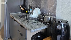 Een moderne keuken met een ingebouwde magnetron, een roestvrijstalen koelkast, een koffiezetapparaat en een vaatwasser.
