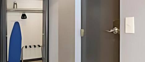 A hallway with a door, a blue surfboard, and a whiteboard on the wall.