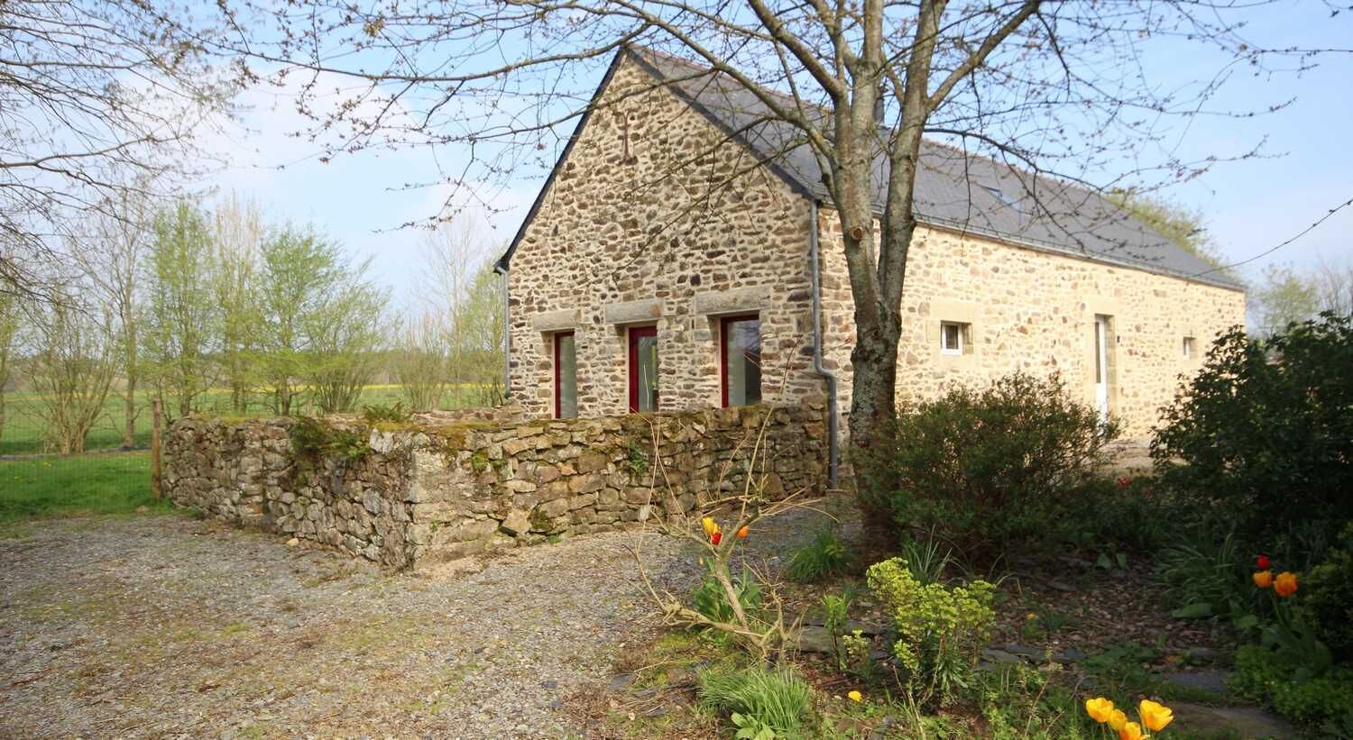Un bâtiment en pierre doté d’un toit en pente, d’un mur en pierre et d’une allée gravillonnée.