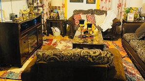 Ein Wohnzimmer mit einer Couch, einem Fernseher, einem Schrank und einem gemusterten Teppich.