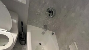 Ein Badezimmer mit Toilette, Badewanne und Duschkopf.