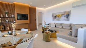 Ein modernes Wohnzimmer mit Sofa, Couchtisch und Fernseher. Eine Treppe führt zu einer weiteren Ebene.