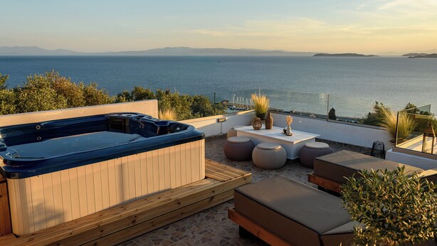 Eine Dachterrasse mit Whirlpool, Sitzbereich und Meerblick.