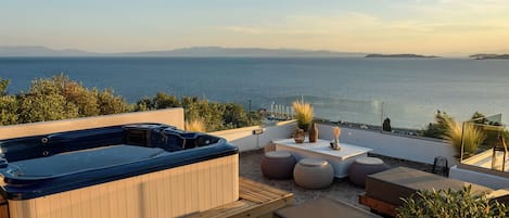 A rooftop terrace with a hot tub, seating area, and a view of the sea.