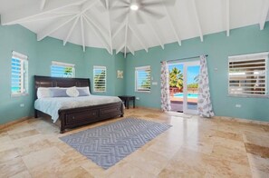 A bedroom with a bed, a ceiling fan, and a view of the outside. -  Luxury Waterfront 3 bedroom Villa in St. Croix Private Pool, & Spacious Deck (Frederiksted)