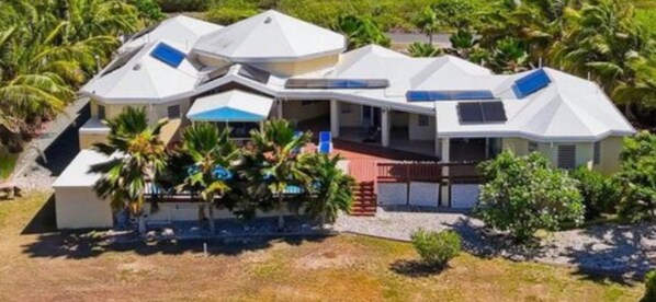 A modern house with multiple roofs, a covered patio, and a pool area surrounded by palm trees. -  Luxury Waterfront 3 bedroom Villa in St. Croix Private Pool, & Spacious Deck (Frederiksted)