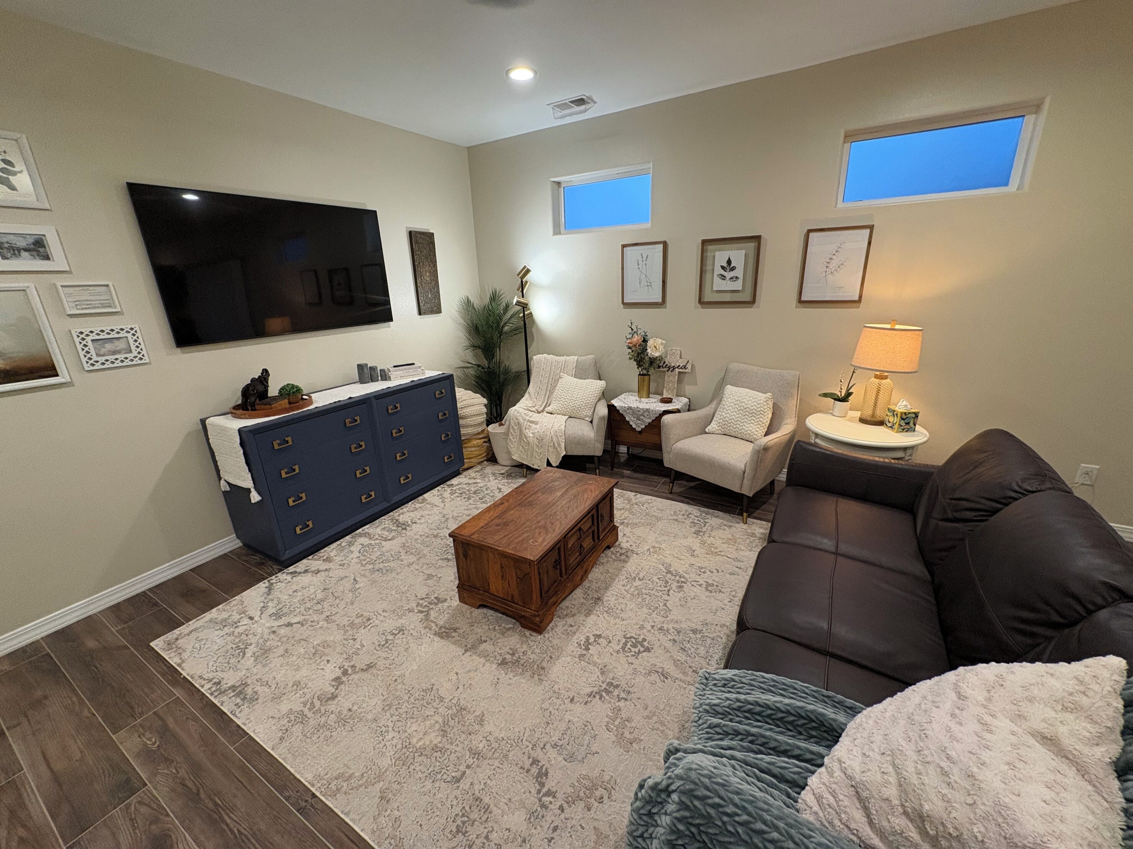 Una sala de estar con sofá, sillón, mesa de centro, televisor y un mueble azul.
