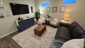 A living room with a sofa, armchair, coffee table, TV, and a blue cabinet.