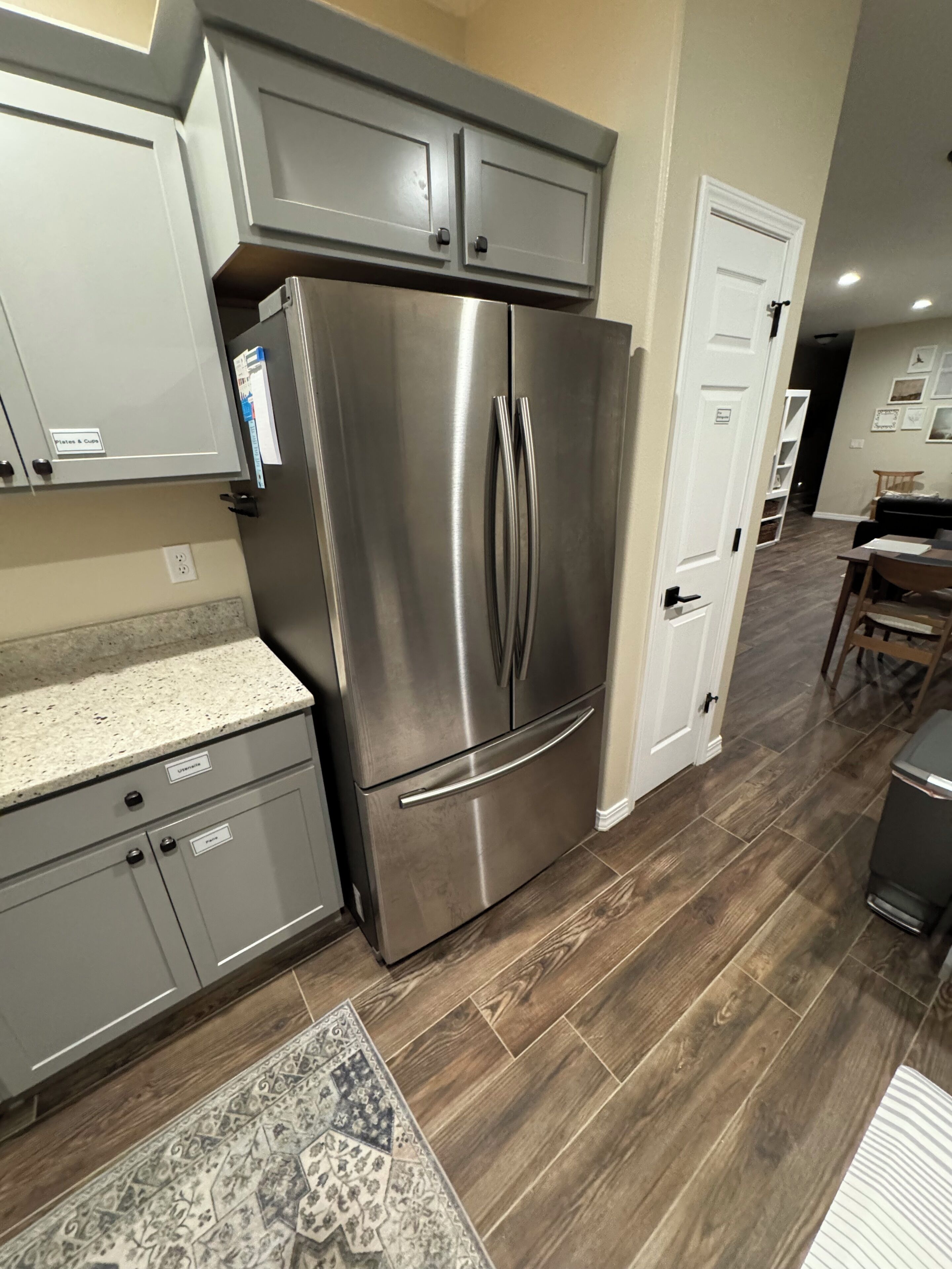 Una cocina con un refrigerador de acero inoxidable, gabinetes grises y un tapete estampado.