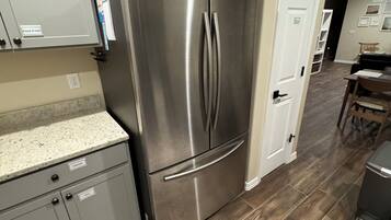 Una cocina con un refrigerador de acero inoxidable, gabinetes grises y un tapete estampado.