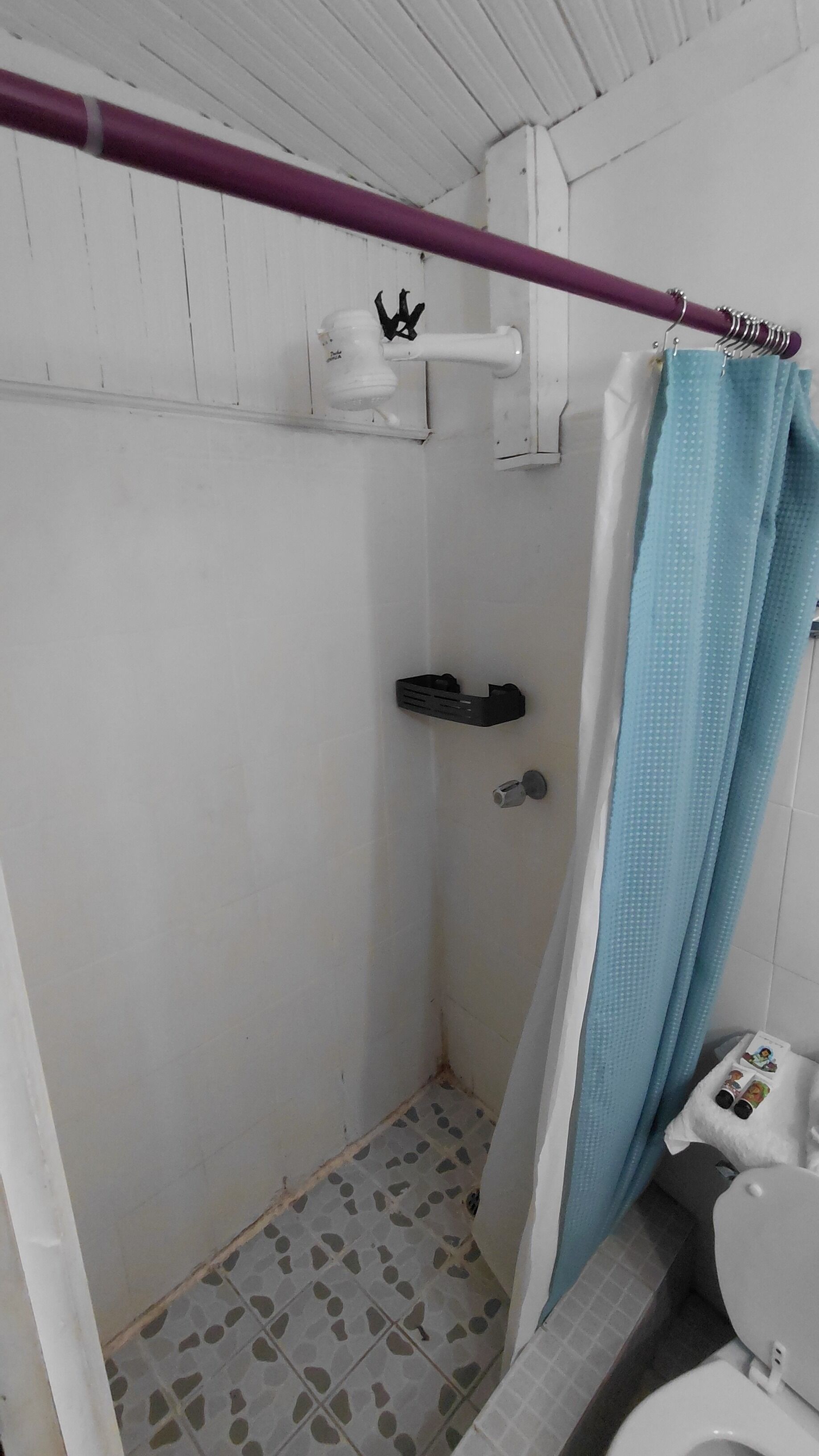 Un baño pequeño y estrecho con ducha, inodoro y un perchero para toallas.