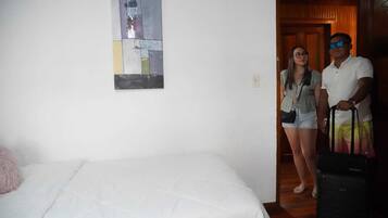 Una habitación de hotel con una cama, un cuadro en la pared y una puerta de madera.