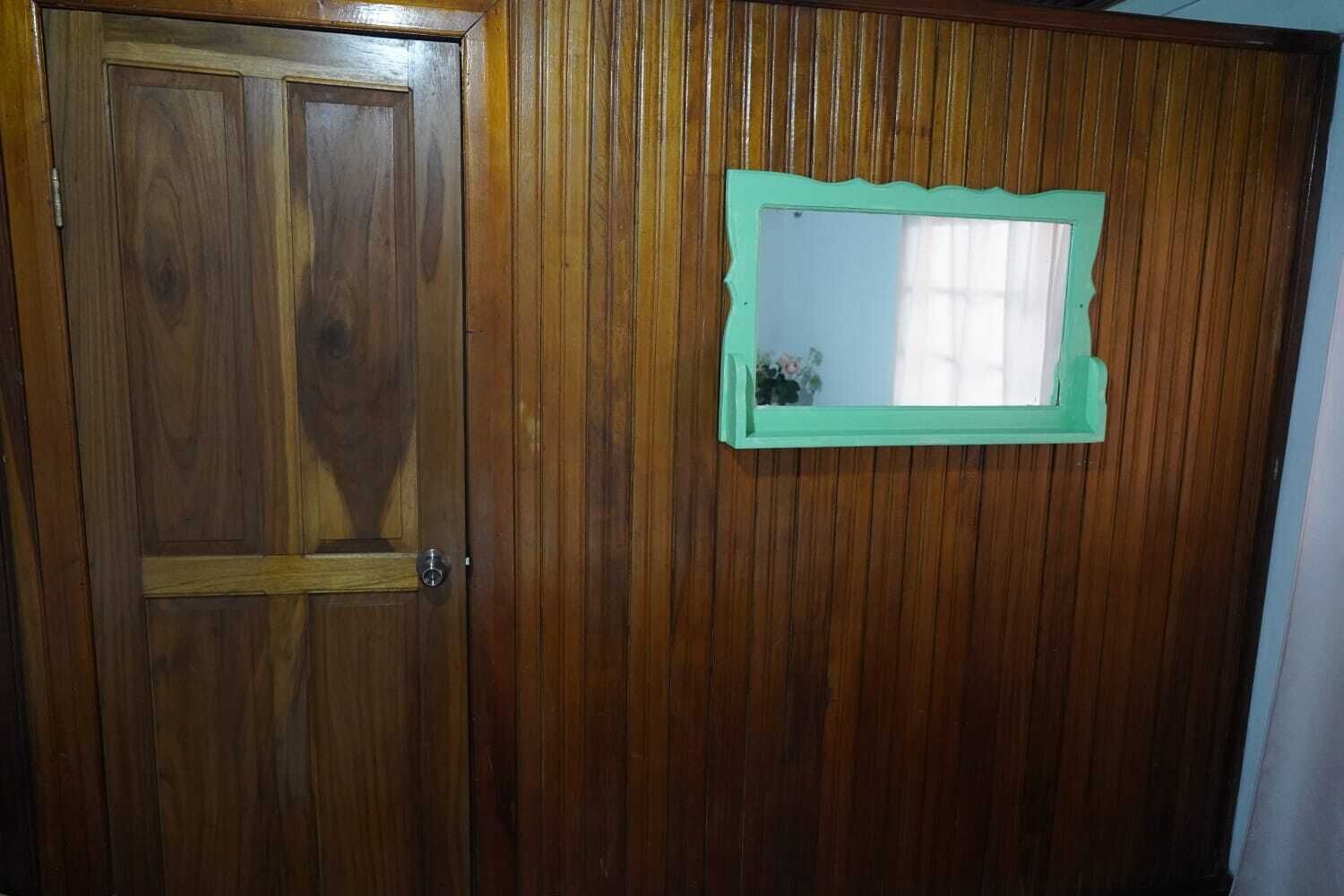 A wooden door with a green-framed mirror.