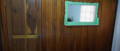 A wooden door with a green-framed mirror.