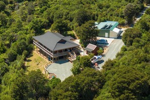 Uma casa grande com uma varanda ampla, uma garagem e um barco atracado na frente.