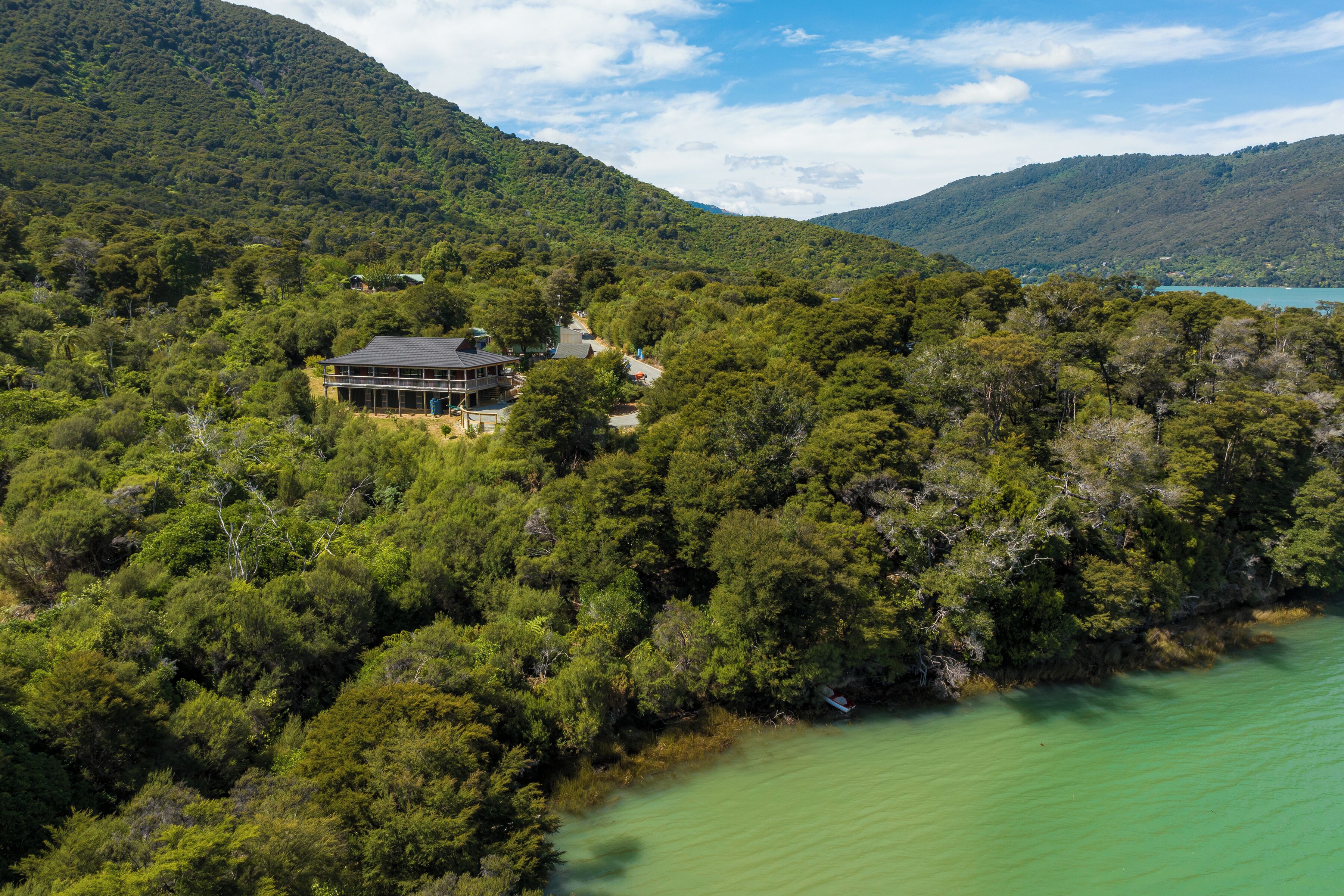 A house surrounded by dense forest with a view of a lake.