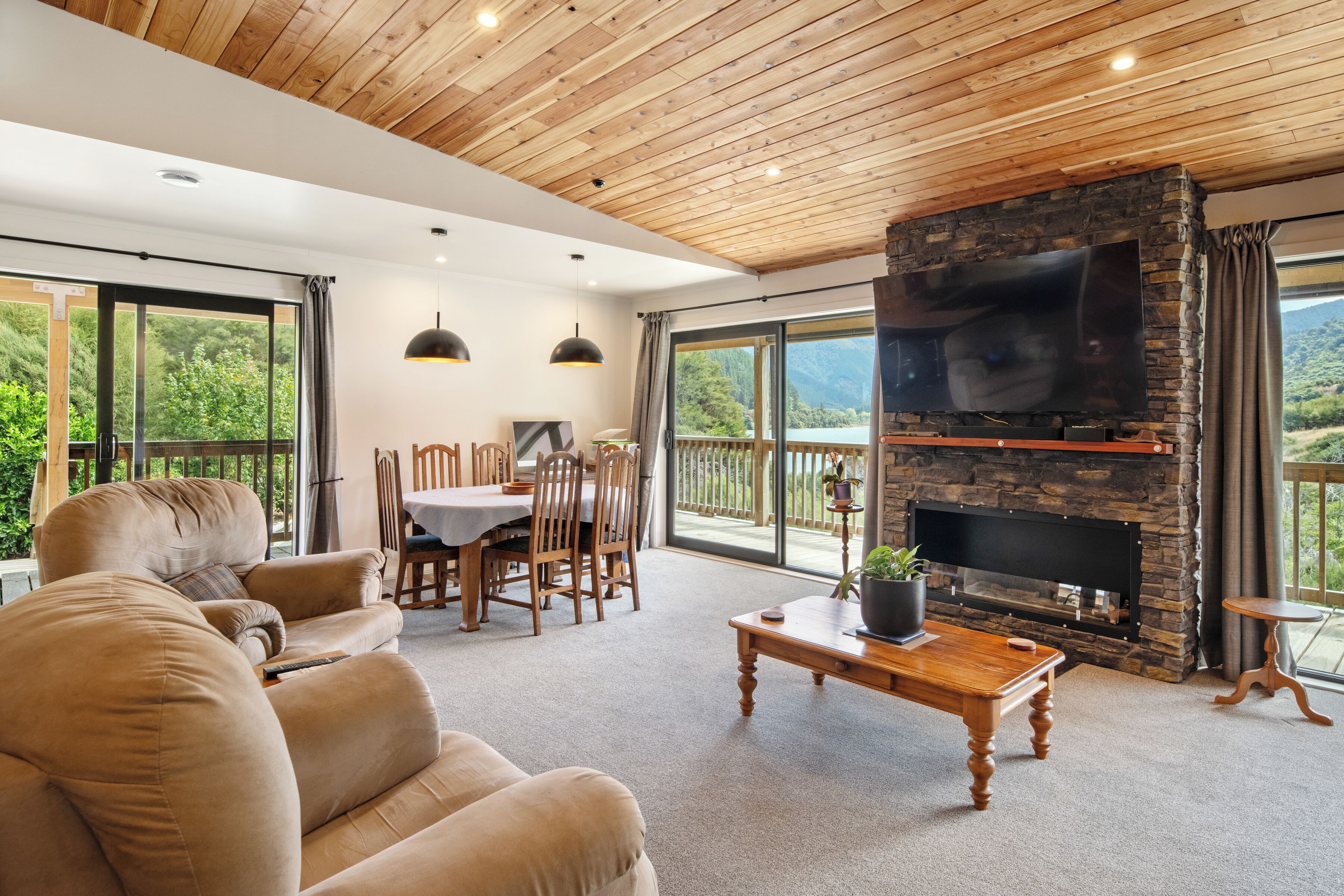 A spacious living room with a stone fireplace, large windows, and a cozy seating area.