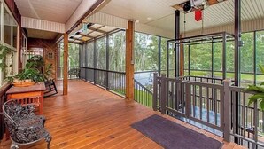 Eine überdachte Veranda mit Holzboden, einer Bank und einem Geländer.