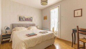 A bedroom with a bed, a nightstand, a chair, a desk, and a window with curtains. - Le Brito - PARENT - Vacation Rental (PARENT)