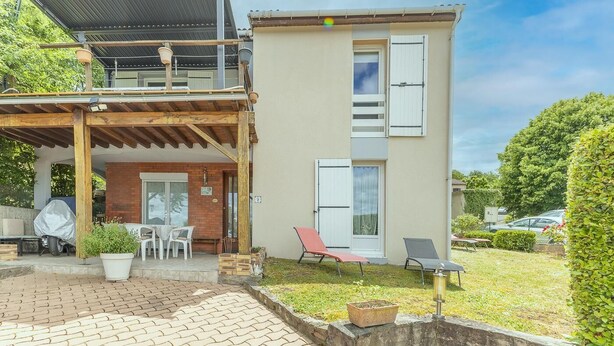 Un bâtiment à deux étages doté d’un patio couvert, d’un espace extérieur aménagé pour s’asseoir et d’un petit jardin.