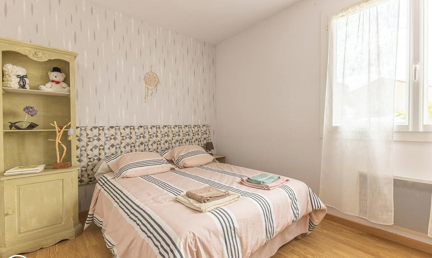 A bedroom with a bed, a nightstand, a wardrobe, and a window with curtains.
