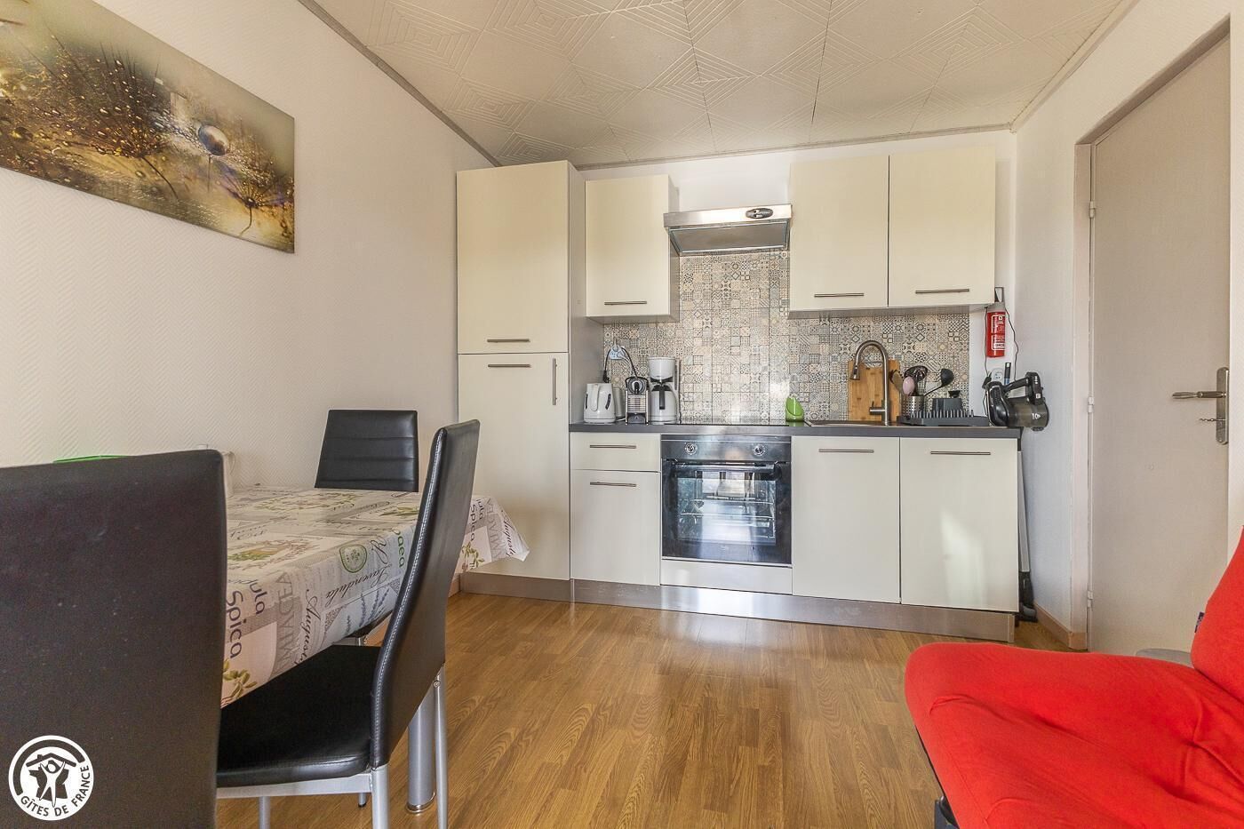 Una cocina compacta con armarios blancos, horno empotrado y cafetera.