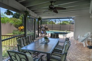 A covered patio with a table and chairs, a ceiling fan, and a view of a backyard with a pool. - Entire House with Seasonally Heated Pool and Waterfall in Naples (Naples)