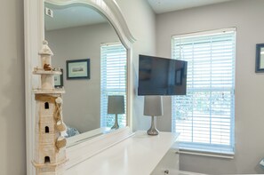A room with a large mirror, a television on a stand, and a window with blinds. - Entire House with Seasonally Heated Pool and Waterfall in Naples (Naples)