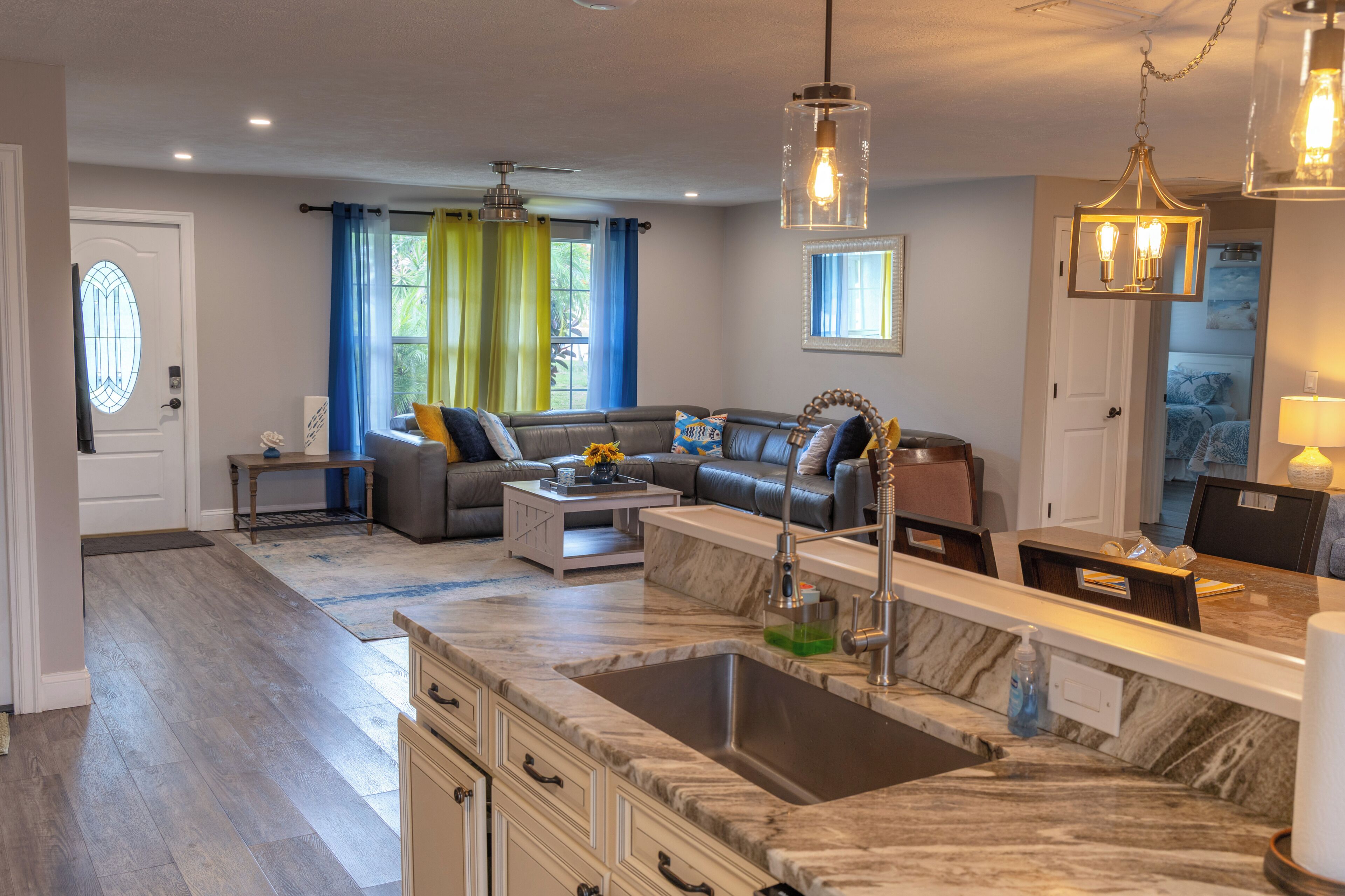 A modern kitchen with a marble countertop, a built-in sink, and a dining area with a table and chairs.
