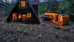 Een chalet met een sterrenhemel, een hottub en een houten terras.