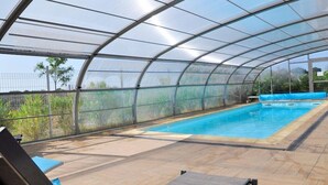Una piscina techada con sillas de descanso y vistas al exterior.