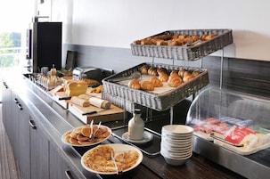 Una mesa de buffet con pan, bollería y productos para el desayuno.