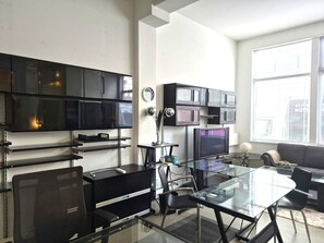 A modern office space with a glass table, black office chairs, a black desk, a television, and a sofa. - Unique  loft like Apt with cache.. in 3 story small 3 unit warehouse conversion. (Montréal)
