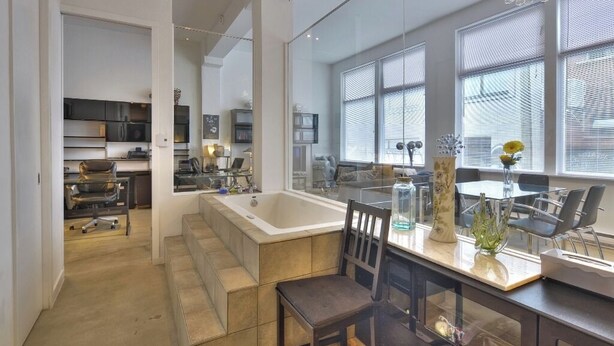 A modern kitchen with a large island, a dining area with a table and chairs, and a large window with blinds. - Unique  loft like Apt with cache.. in 3 story small 3 unit warehouse conversion. (Montréal)