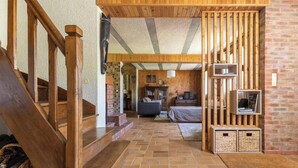 A wooden staircase leading to a living area with a fireplace, a sofa, and a television. - La Pruneyre - ESPINCHAL (ESPINCHAL)