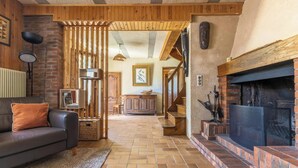 A cozy living room with a fireplace, a sofa, and a staircase leading to another room. - La Pruneyre - ESPINCHAL (ESPINCHAL)