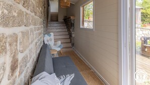 A stone wall, a staircase, a window, and a sofa in a room. - Murat's Cocoon - MURAT LE QUAIRE (MURAT LE QUAIRE)